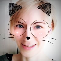 A white, female-looking person with short blonde hair, filters are used on the photo that show cat ears, whiskers and big round glasses