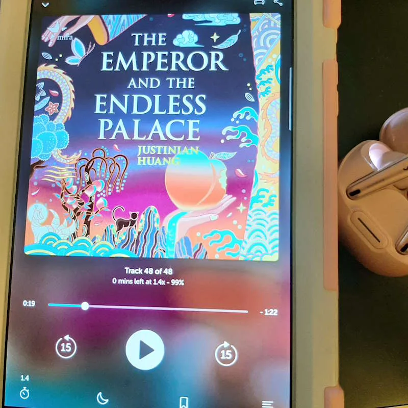 Photo of a tablet and earbuds, the tablet shows the Libro FM player with The Emperor and the Endless Palace playing, one of the best new audiobooks this month